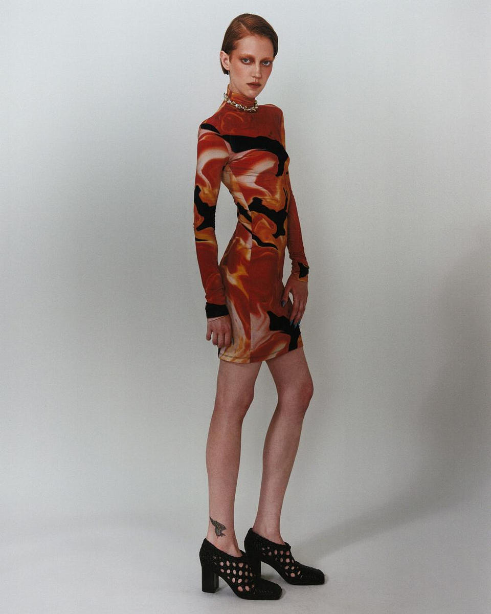 Lookbook-style studio image of a model in a red patterned dress against a clean background