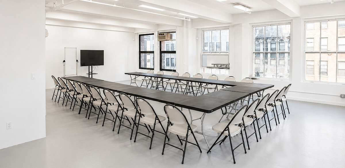 Boardroom-style meeting table layout with chairs in a bright Midtown Manhattan rental space near Penn Station