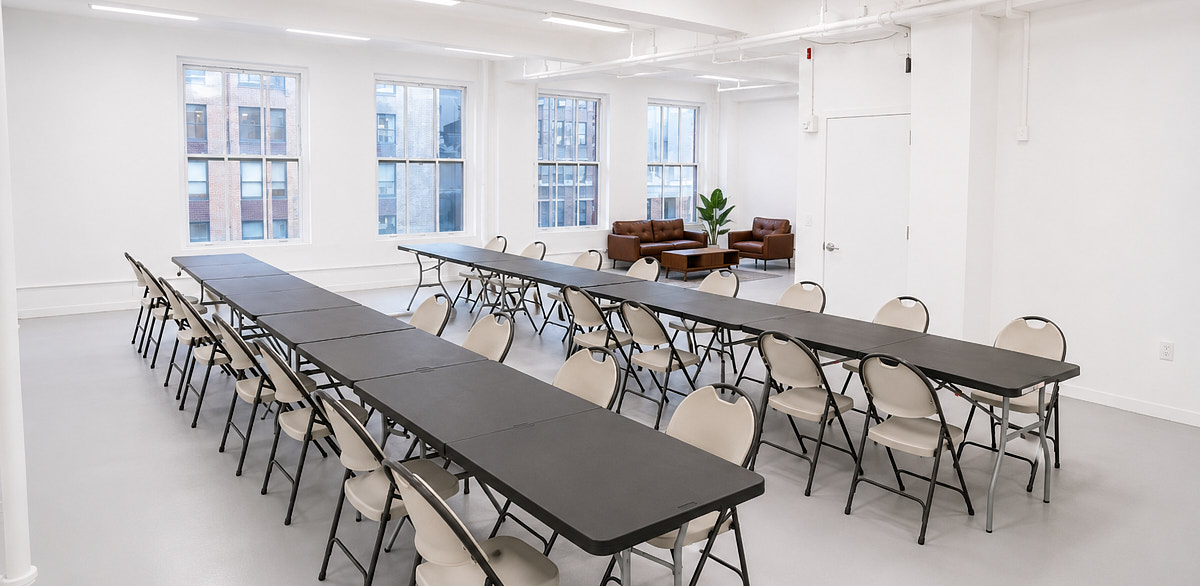 Workshop table layout in a bright Midtown event space with long tables, chairs, and natural light