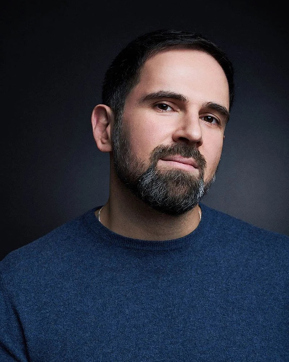 Casual men's portrait with a navy background and soft studio lighting