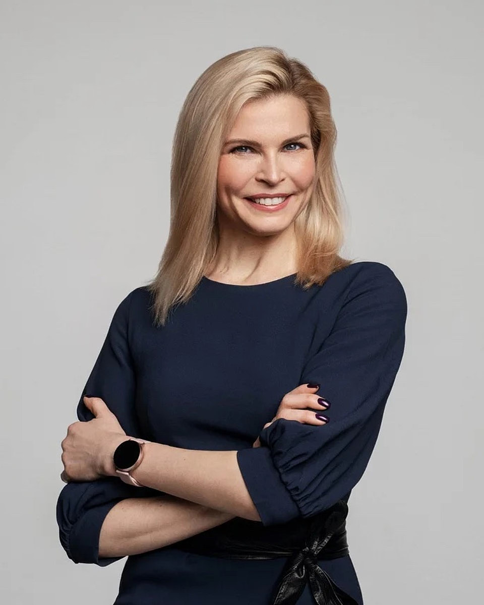 Professional women's headshot with arms crossed against a light gray studio background