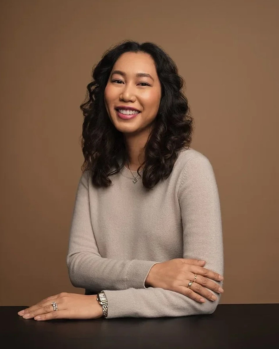 Seated portrait of a woman in a beige top with a warm studio background