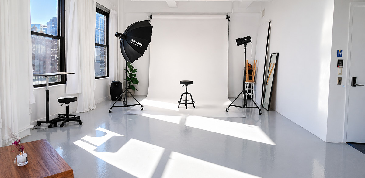 Bright photo studio setup for product and content shoots with open floor space, lighting equipment, and window light